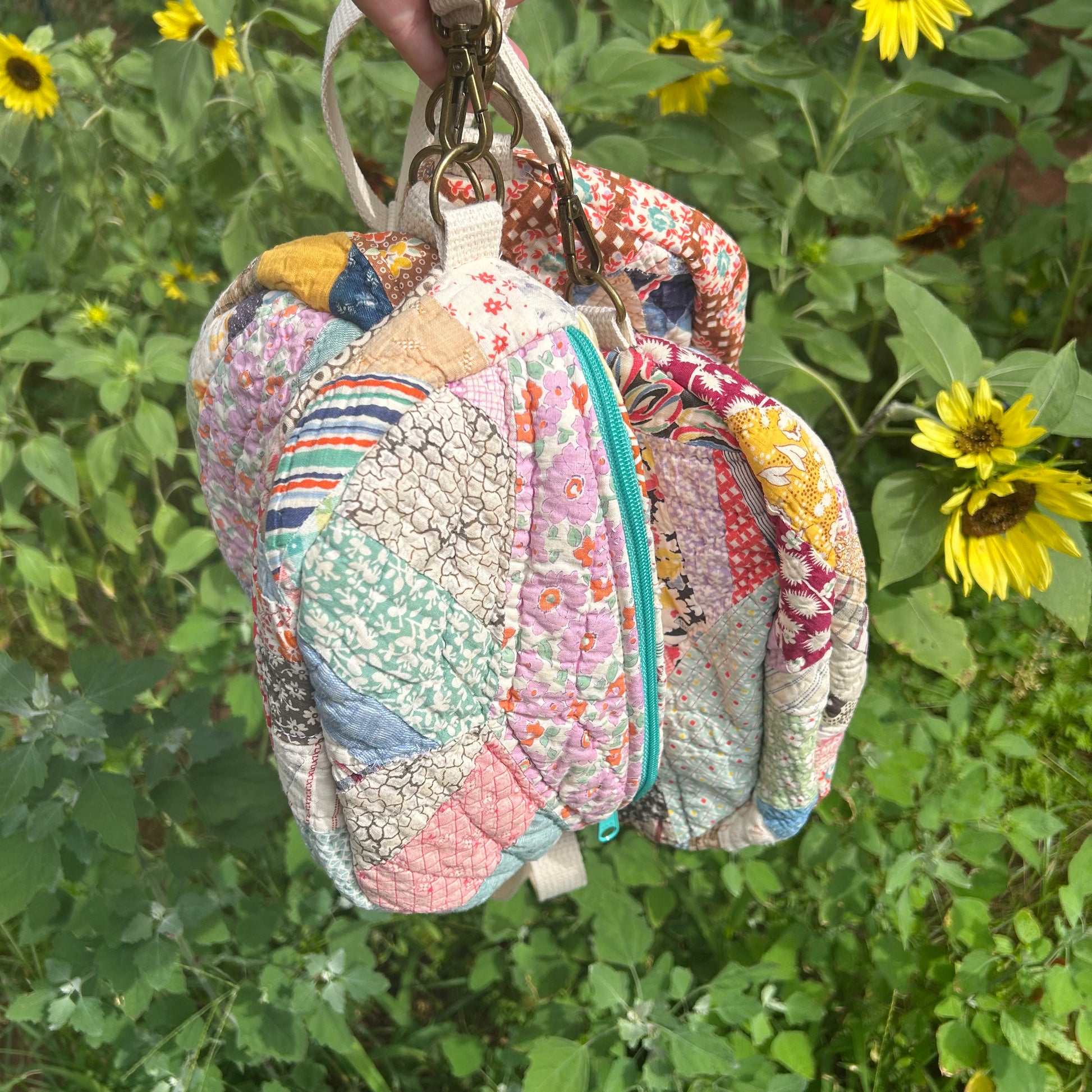 Colorful quilted bag hanging among sunflowers and greenery