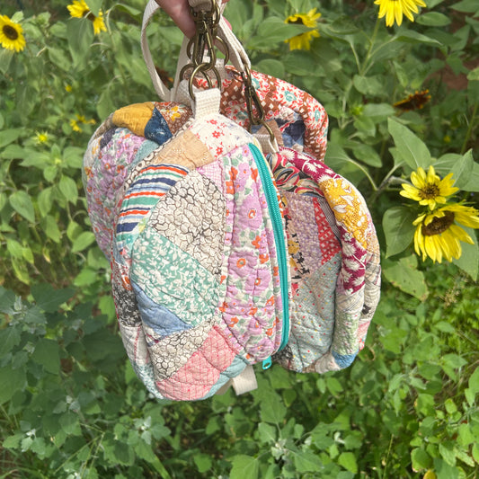 Colorful quilted bag hanging among sunflowers and greenery