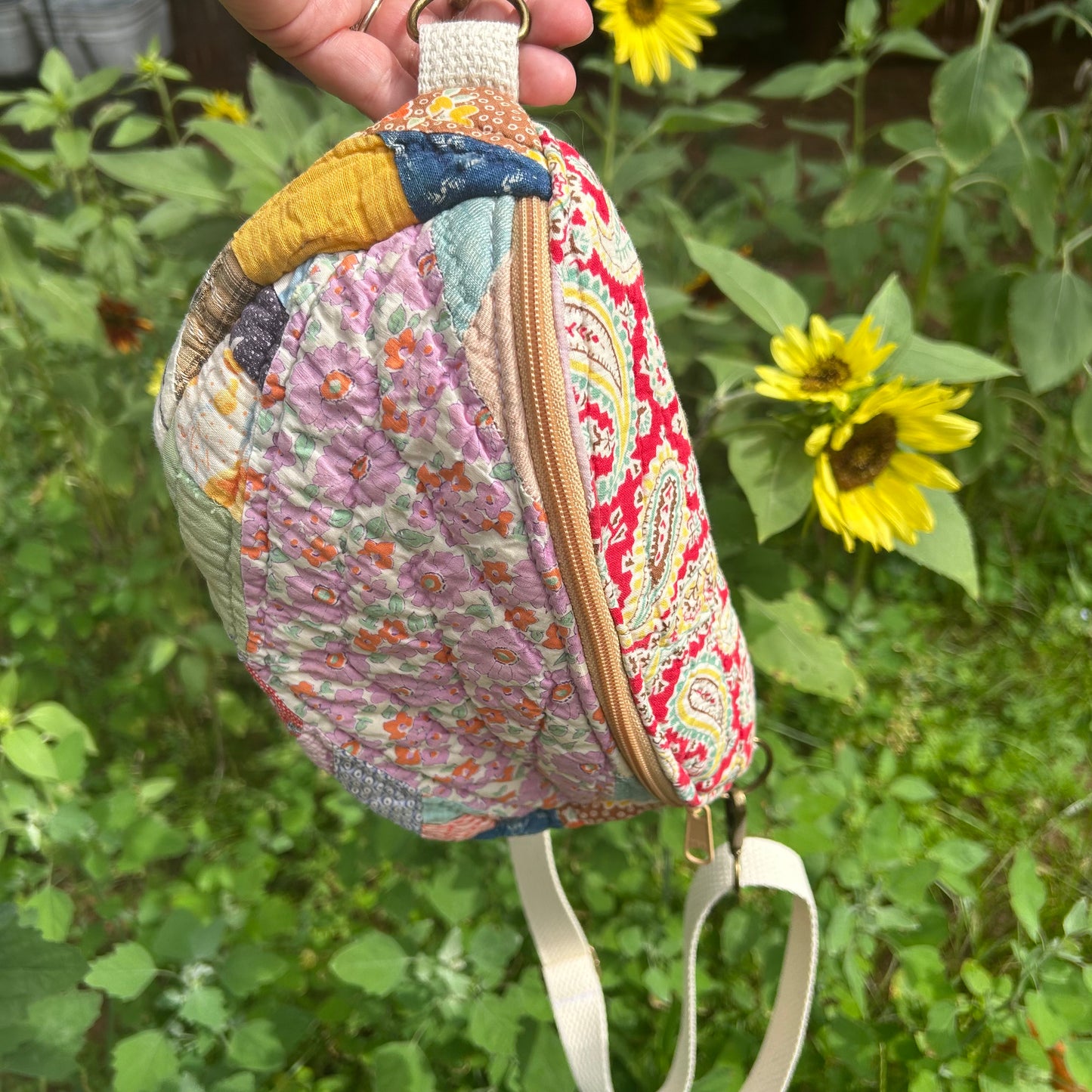 Colorful patterned pouch held in front of sunflowers